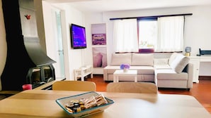 A living room with a sofa, a television, a fireplace, and a dining table with a bowl of snacks. - Just Restored close to Franklin College and Lugano (Montagnola)