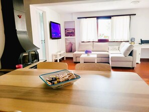Una sala de estar con sofá, televisión, chimenea y mesa de comedor con un tazón de bocadillos.