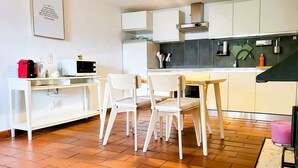 A kitchen with white cabinets, a microwave, a kettle, and a table with chairs. - Just Restored close to Franklin College and Lugano (Montagnola)