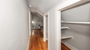 A narrow hallway with wooden flooring, white walls, and built-in shelving units. - Suites on Main 3 (Covington)