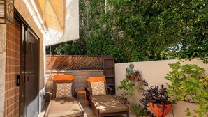 Une terrasse dotée de meubles en osier, d’un mur en bois et de plantes en pot.