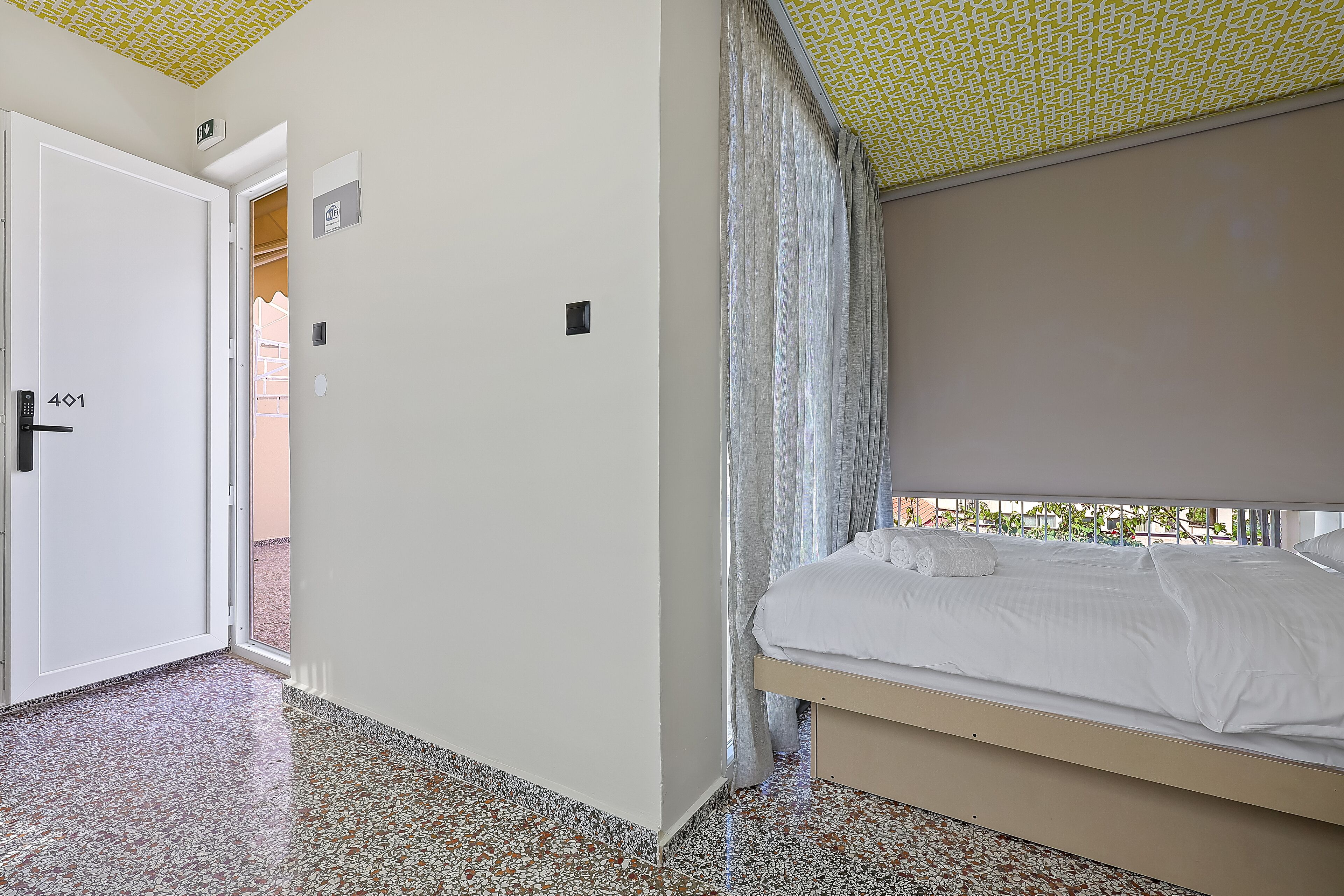 Ein Hotelzimmer mit Bett, Tür und Blick nach draußen.