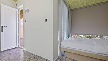 Ein Hotelzimmer mit Bett, Tür und Blick nach draußen.