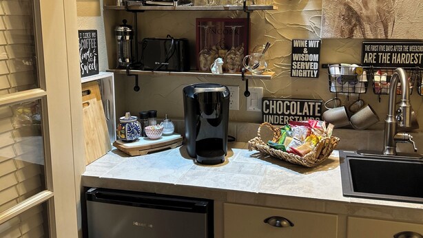Une cuisine équipée d’une machine à café, d’étagères où sont rangés des verres et d’un panneau d’information sur le chocolat.