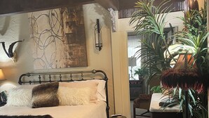 Une chambre confortable avec un lit, une table de chevet et une grande plante en pot.
