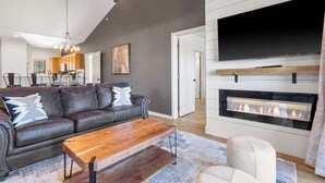 A modern living room with a leather sofa, wooden coffee table, and a fireplace. - T Time Getaway - Overlooking Golf Views! (Branson West)