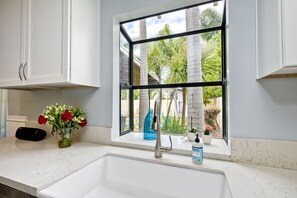 Enjoy a serene view of lush palm trees from this kitchen's large window.