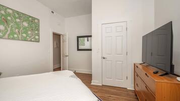 Un dormitorio con cama, cómoda, televisor y puerta.