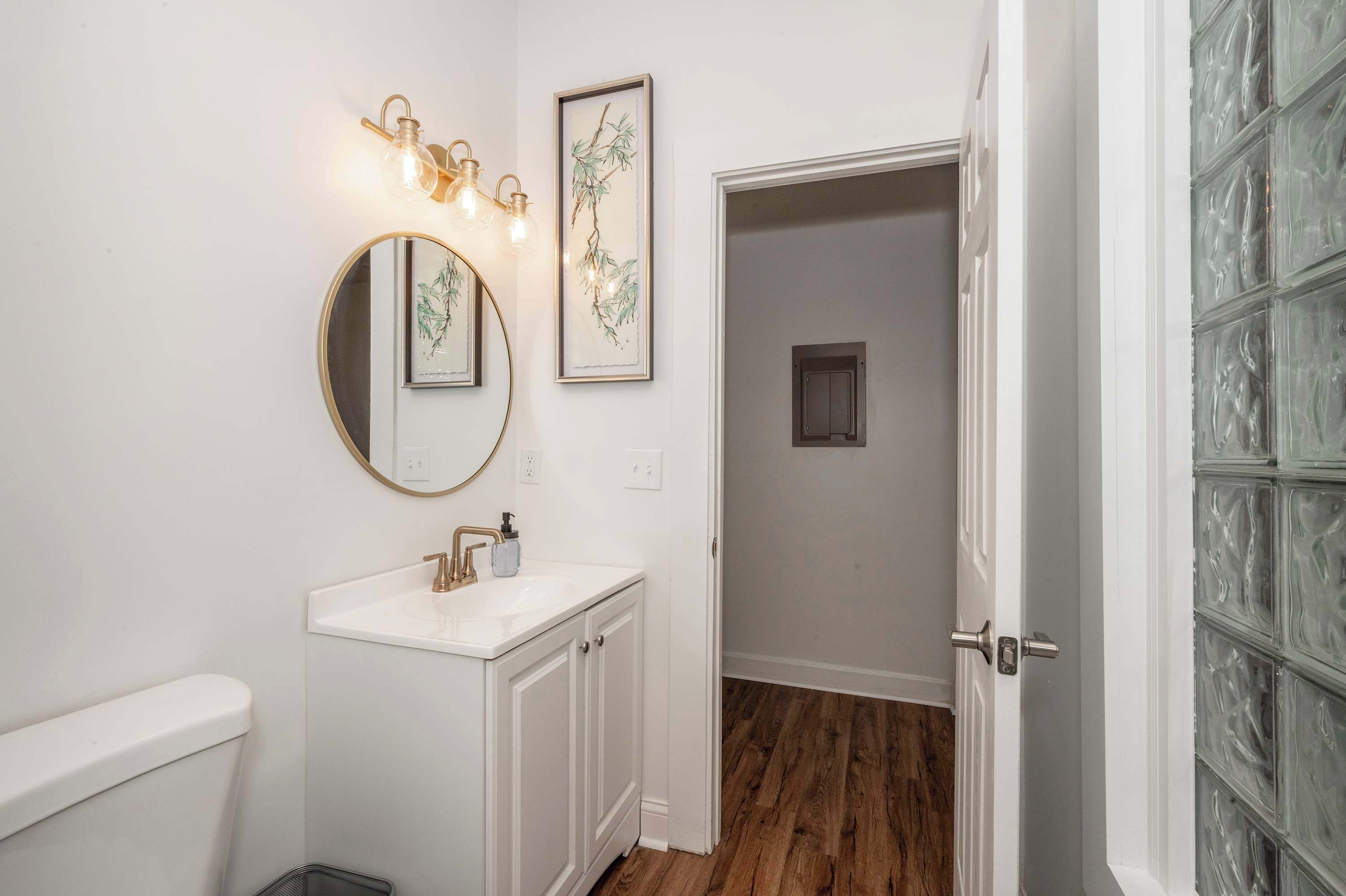 A bathroom with a white sink, a round mirror, and wall-mounted lights.