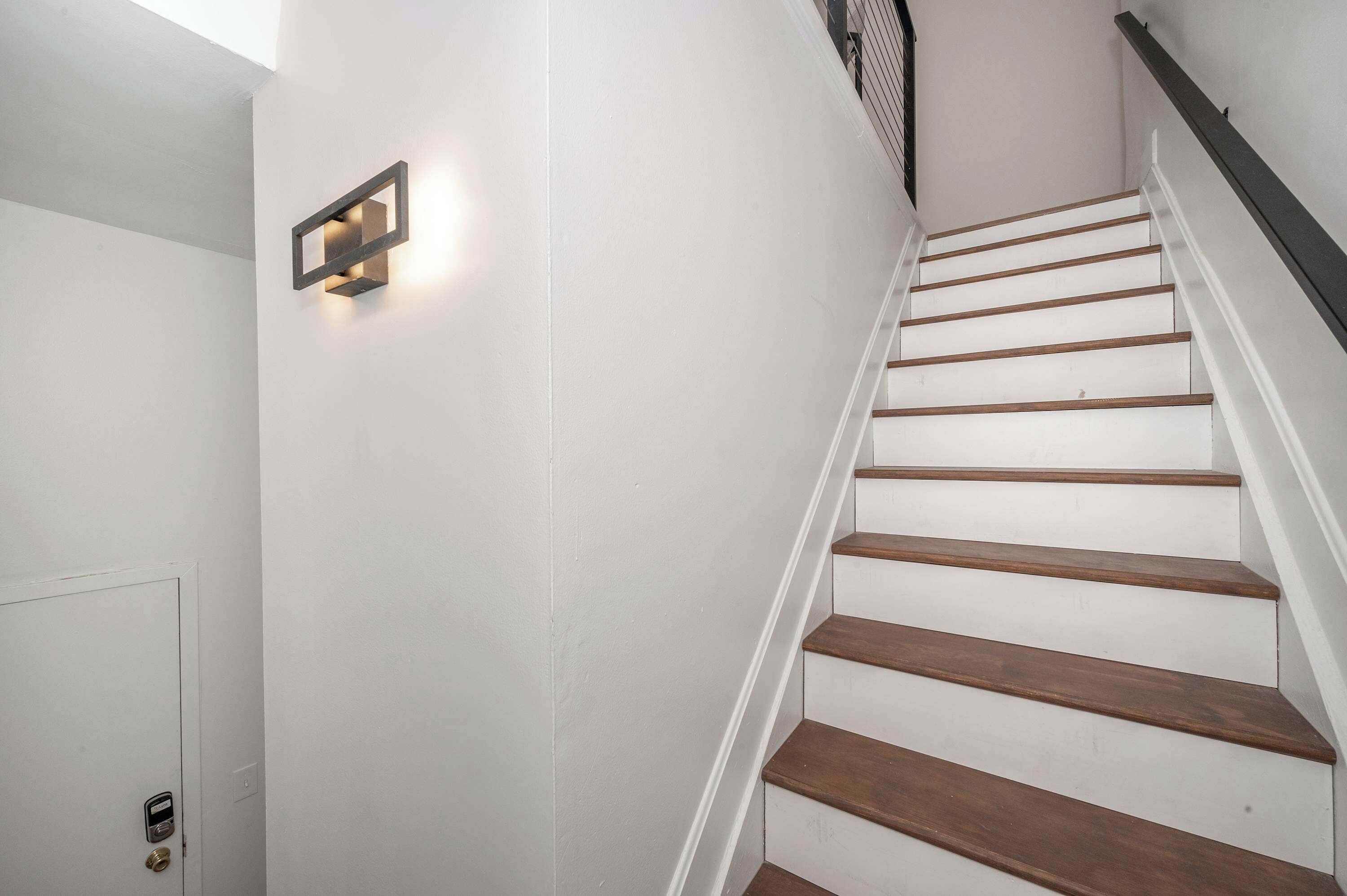 Una escalera con escalones de madera y una pared blanca.
