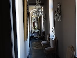 Un pasillo con candelabros ornamentados, muebles antiguos y una alfombra estampada.