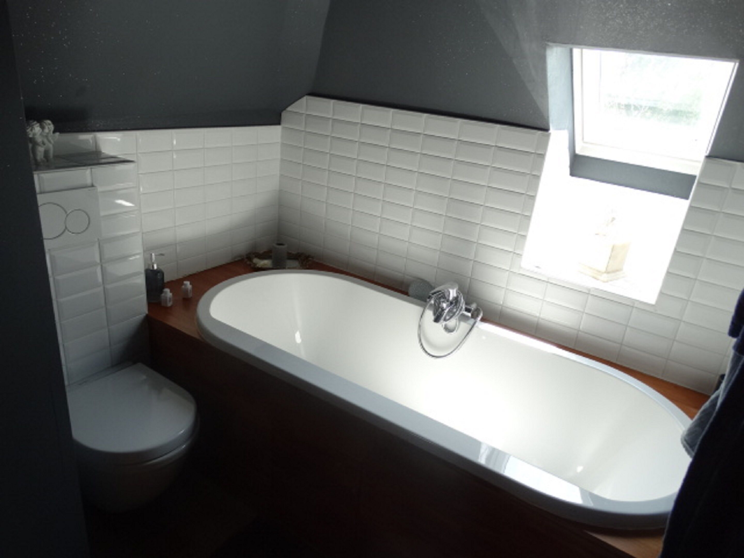 A bathroom with a bathtub, toilet, and a window.