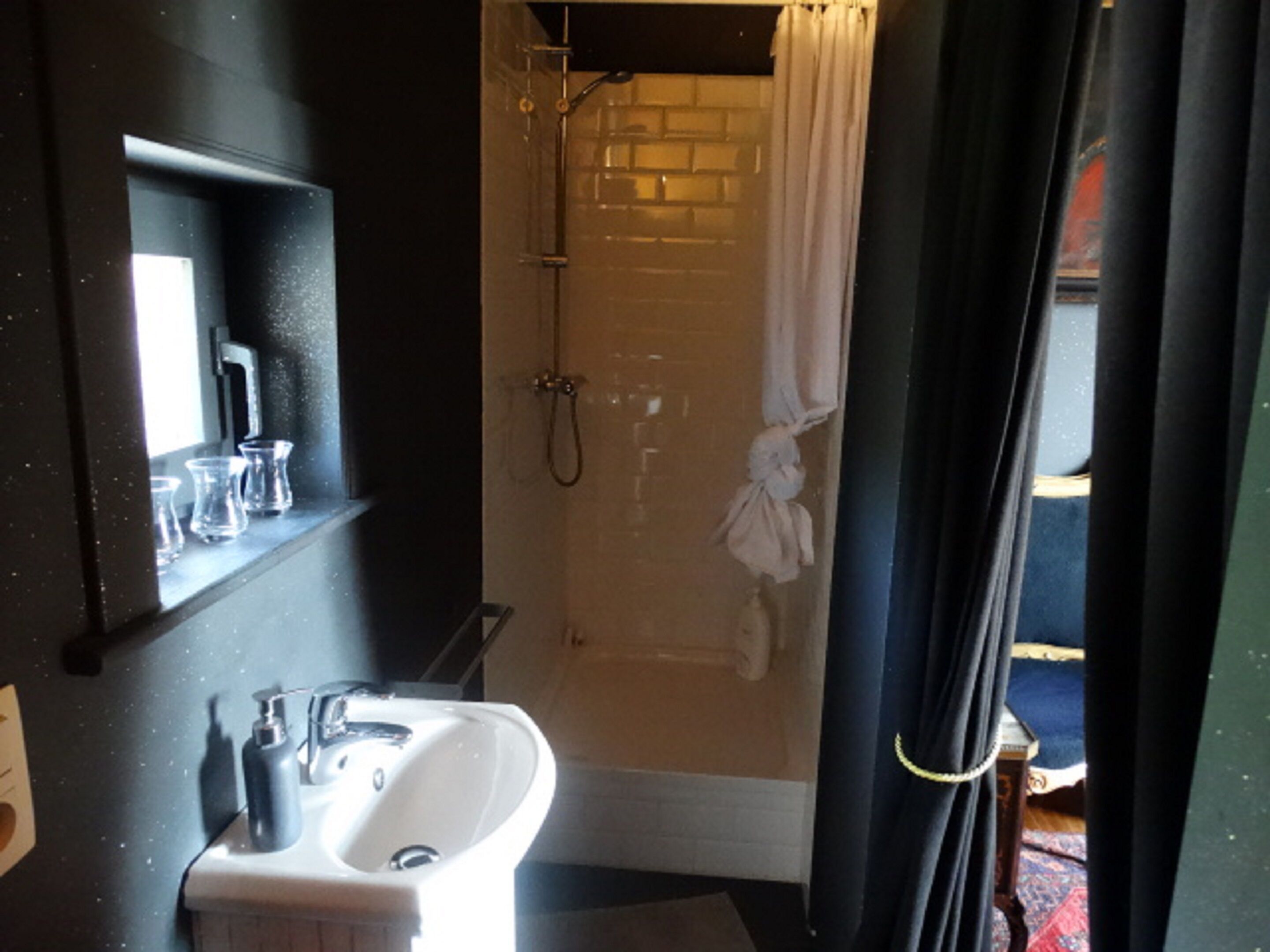 Un baño con lavabo blanco, espejo y ducha con cortina.