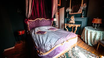 Une chambre à coucher avec un grand lit, un lustre, un miroir et une petite table avec une lampe.