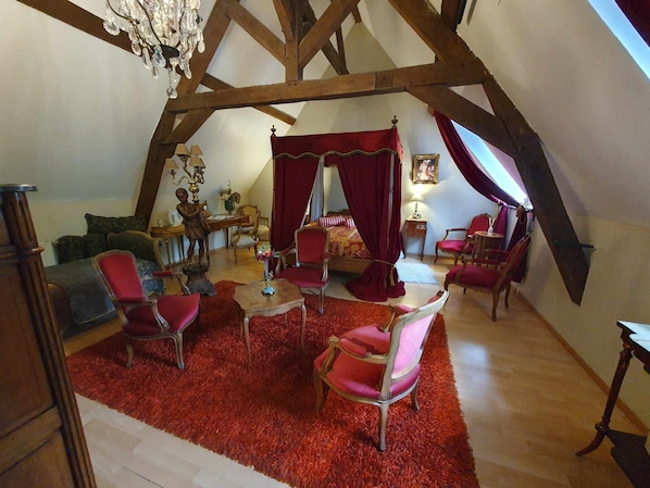 A cozy, well-lit attic bedroom with a sloped ceiling, a red carpet, and a canopy bed. - Le Domaine Du Château Blanc à 10 minutes de Pairi Daiza (Jurbise)