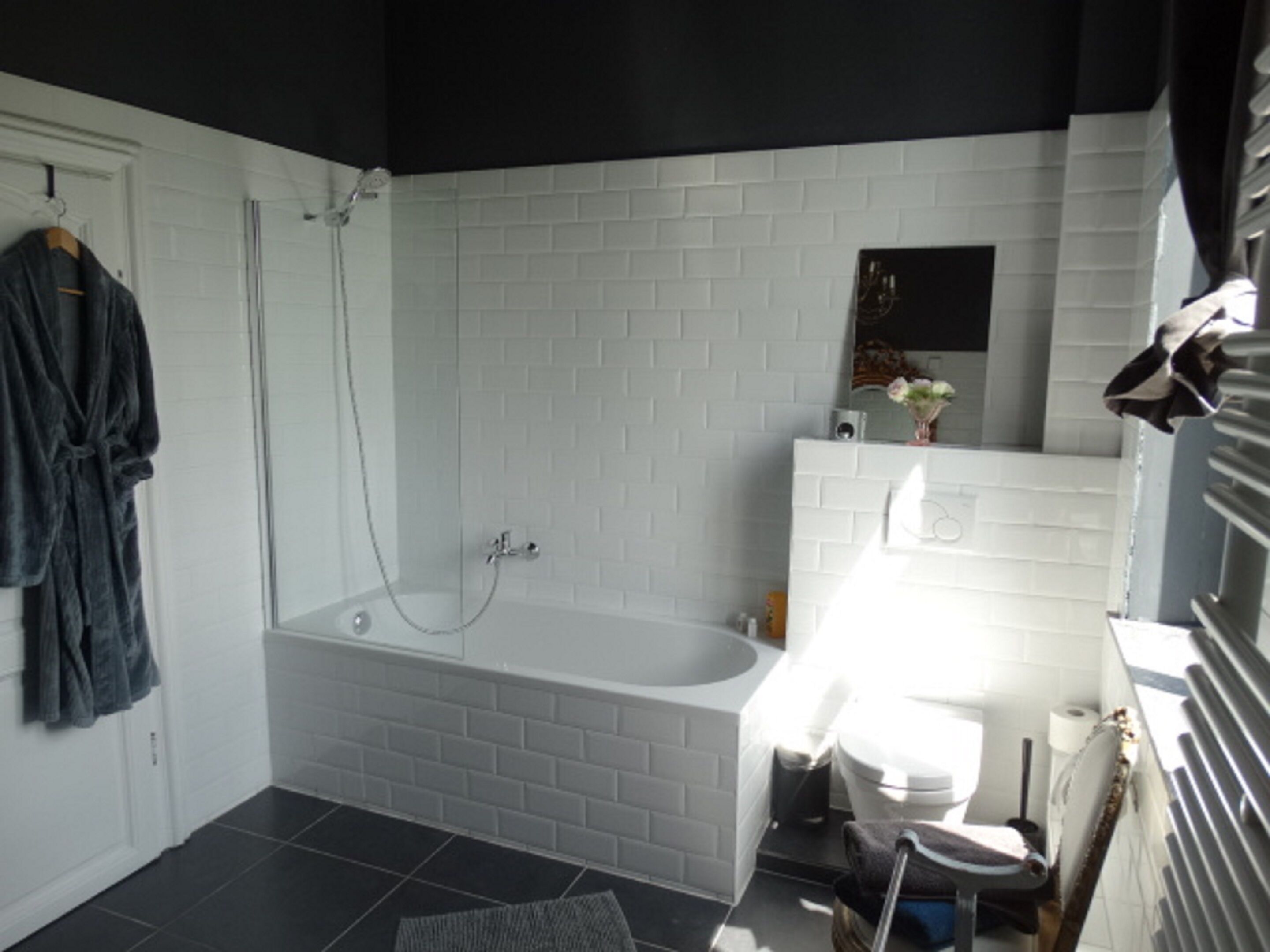 A bathroom with a white bathtub, a toilet, and a shower.