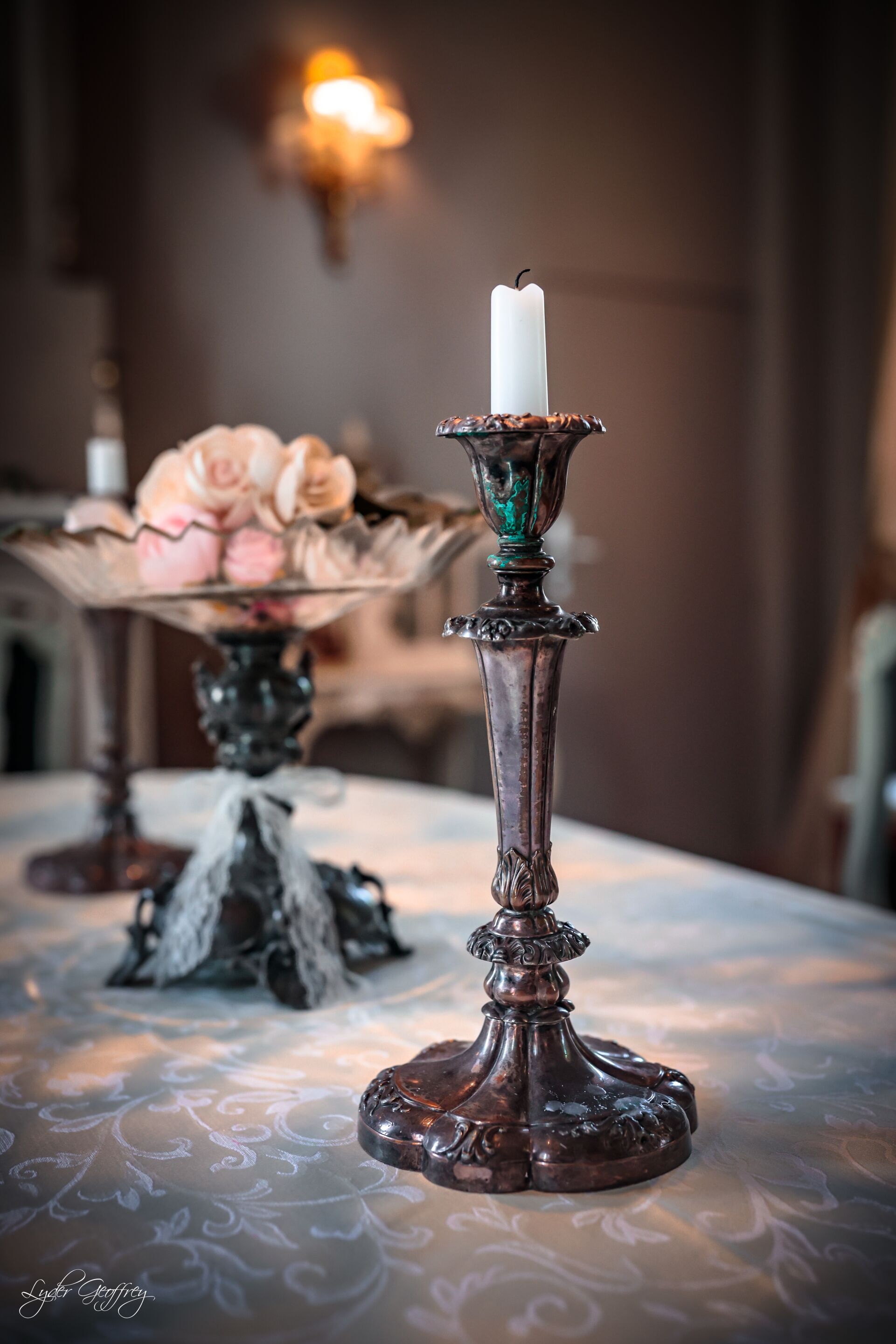 Un candelabro con una vela blanca sobre una mesa con mantel estampado.