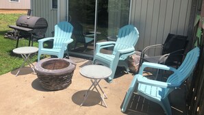 Un patio con mobiliario exterior, una parrilla y un brasero.