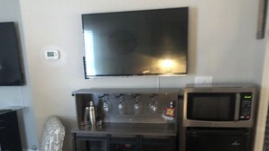 Una cocina compacta con televisión de pantalla plana, microondas y refrigerador.