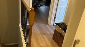Una escalera con barandilla de madera y una puerta que da a una habitación con escritorio y silla.