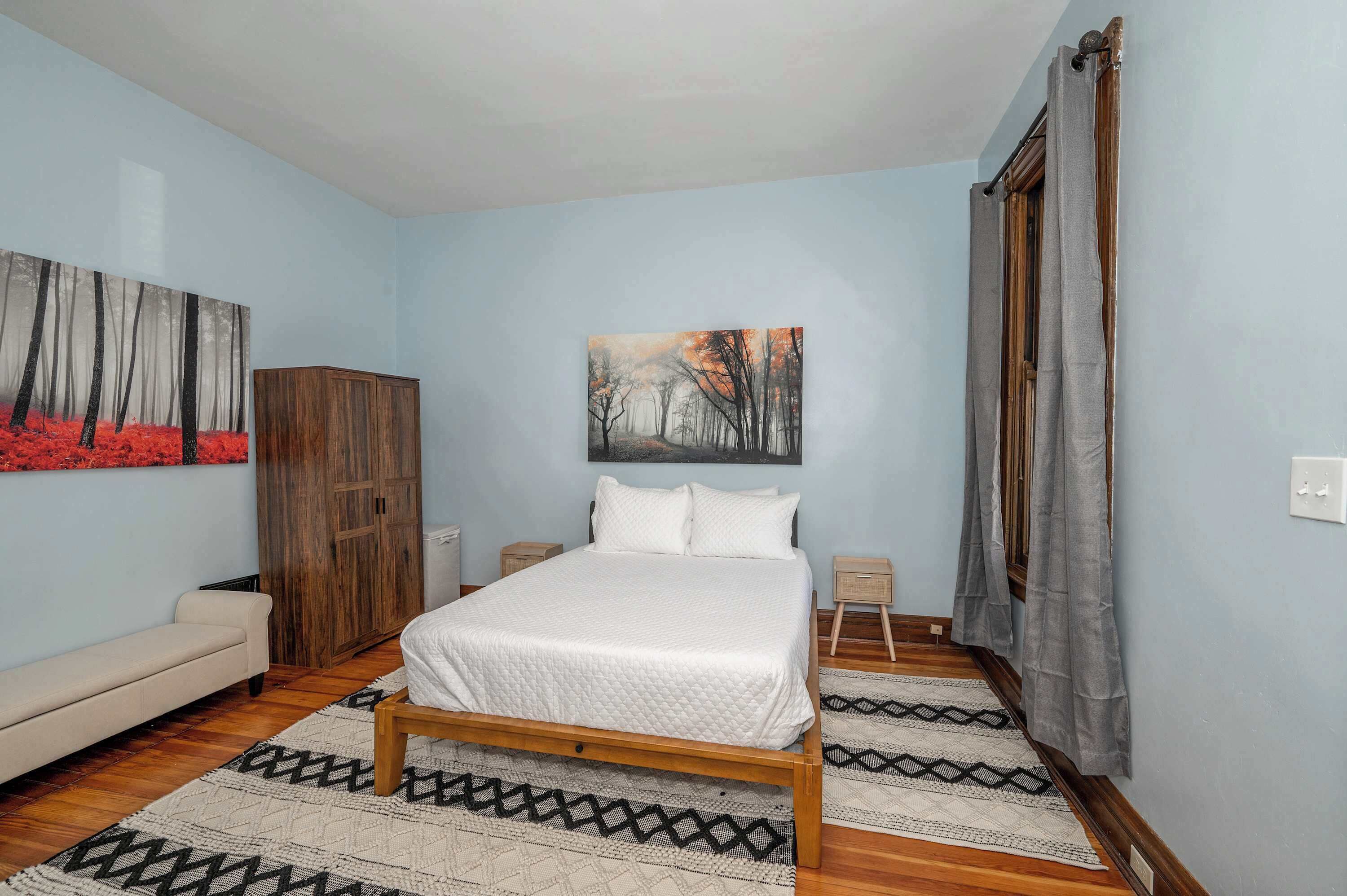 A bedroom with a wooden bed, a sofa, a wardrobe, and a painting on the wall.