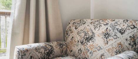 A corner of a room with a patterned sofa and a curtain.
