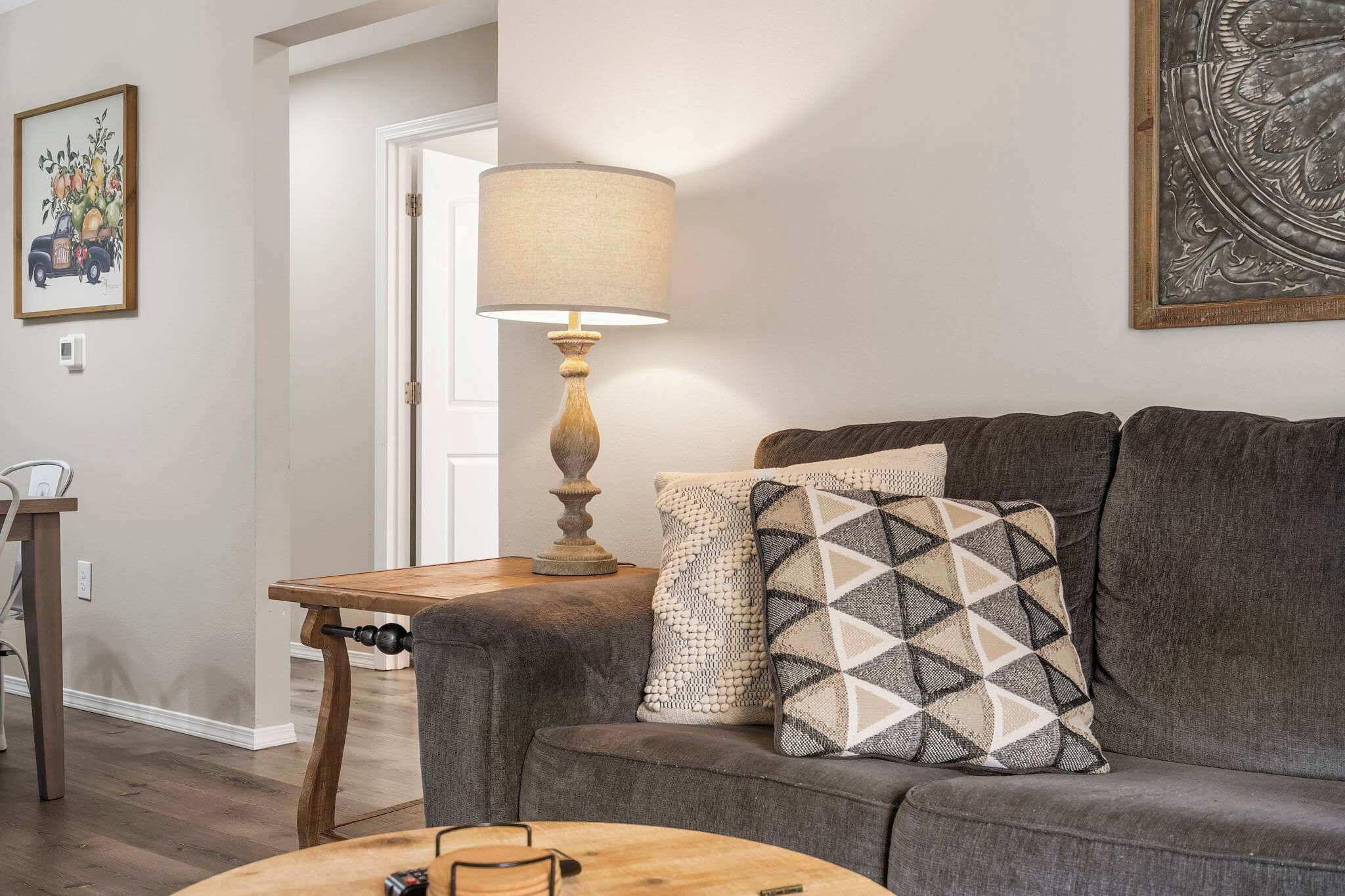 A living room with a grey sofa, a wooden coffee table, a lamp, and a framed picture on the wall.