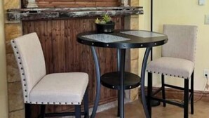 A room with a stone wall, a wooden-framed window, two chairs, a small round table, and a floor lamp. - Mountain Apartment, Minutes to Resorts & Services (Ogden)