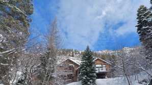 A snow-covered lodge with a wooden exterior, surrounded by trees and a mountain backdrop. - Mountain Apartment, Minutes to Resorts & Services (Ogden)