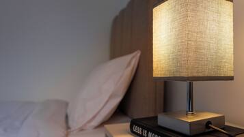 Ein Nachttisch mit Lampe und dem Buch 'Less is More' von Jason Hickel.
