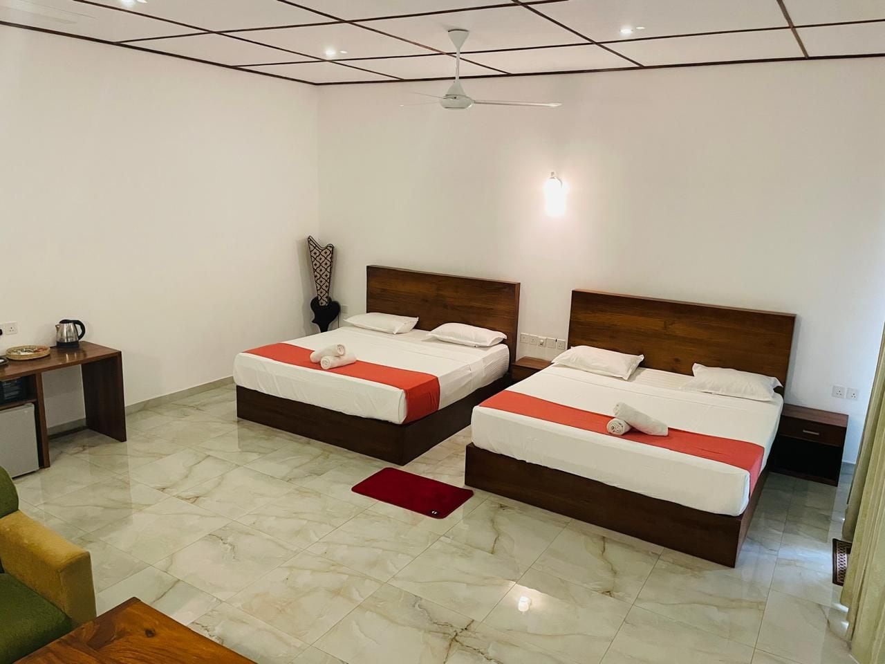 A hotel room with two beds, a desk, and a small kitchenette.
