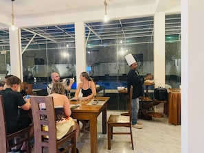 Un restaurant avec des tables et des chaises en bois, de grandes fenêtres et un aménagement intérieur moderne.