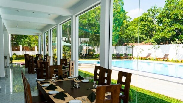 Un espace repas offrant une vue sur une piscine et une végétation luxuriante.
