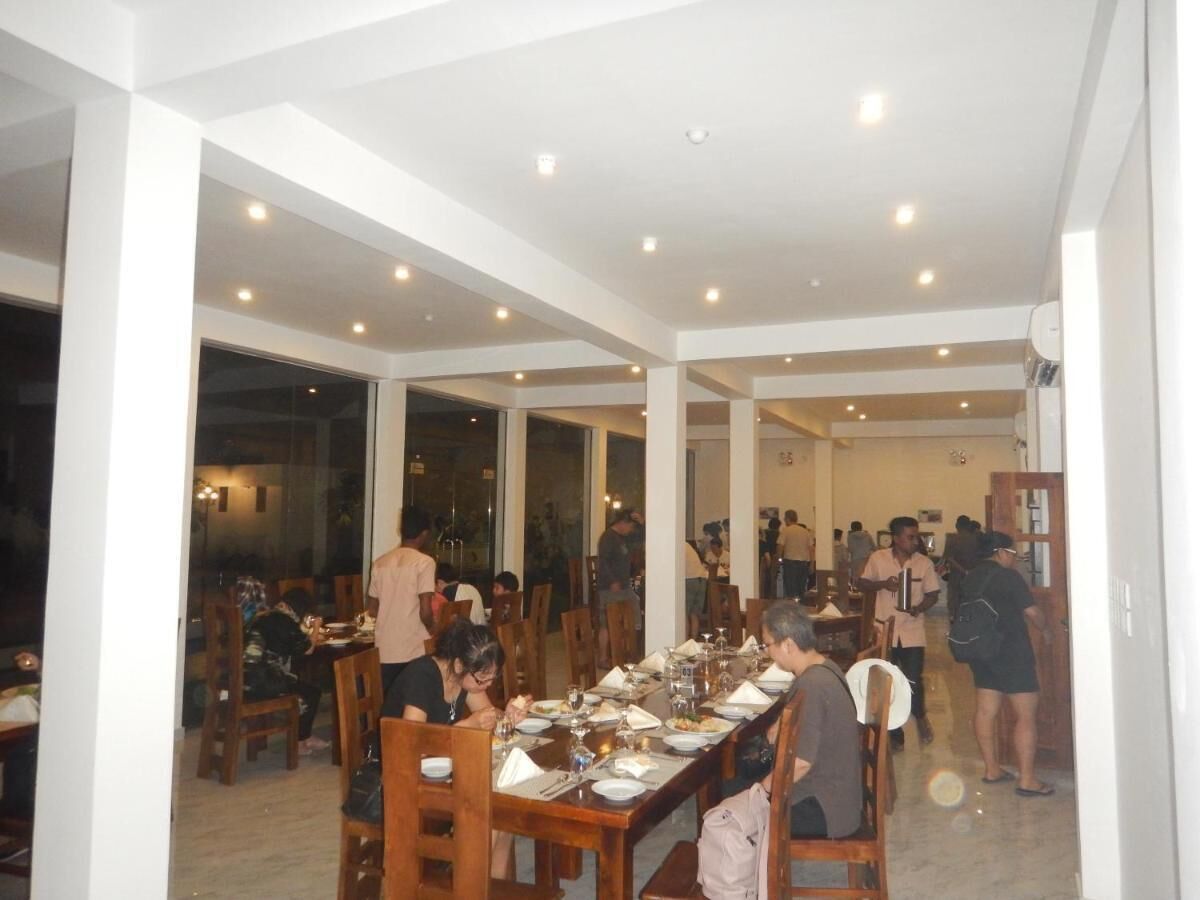 Un'ampia sala da pranzo con diversi tavoli e sedie, ampie finestre e un soffitto alto con illuminazione a incasso.