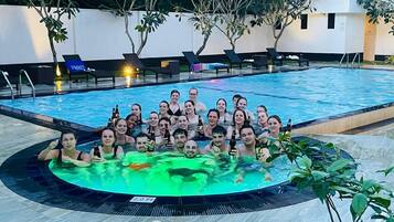 Eine Gruppe von Personen in einem Schwimmbad mit Liegestühlen und einem Whirlpool.