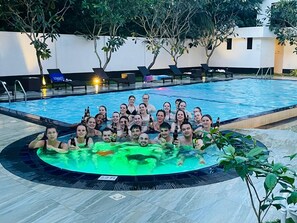 Een groep mensen in een zwembad met ligbedden en een jacuzzi.
