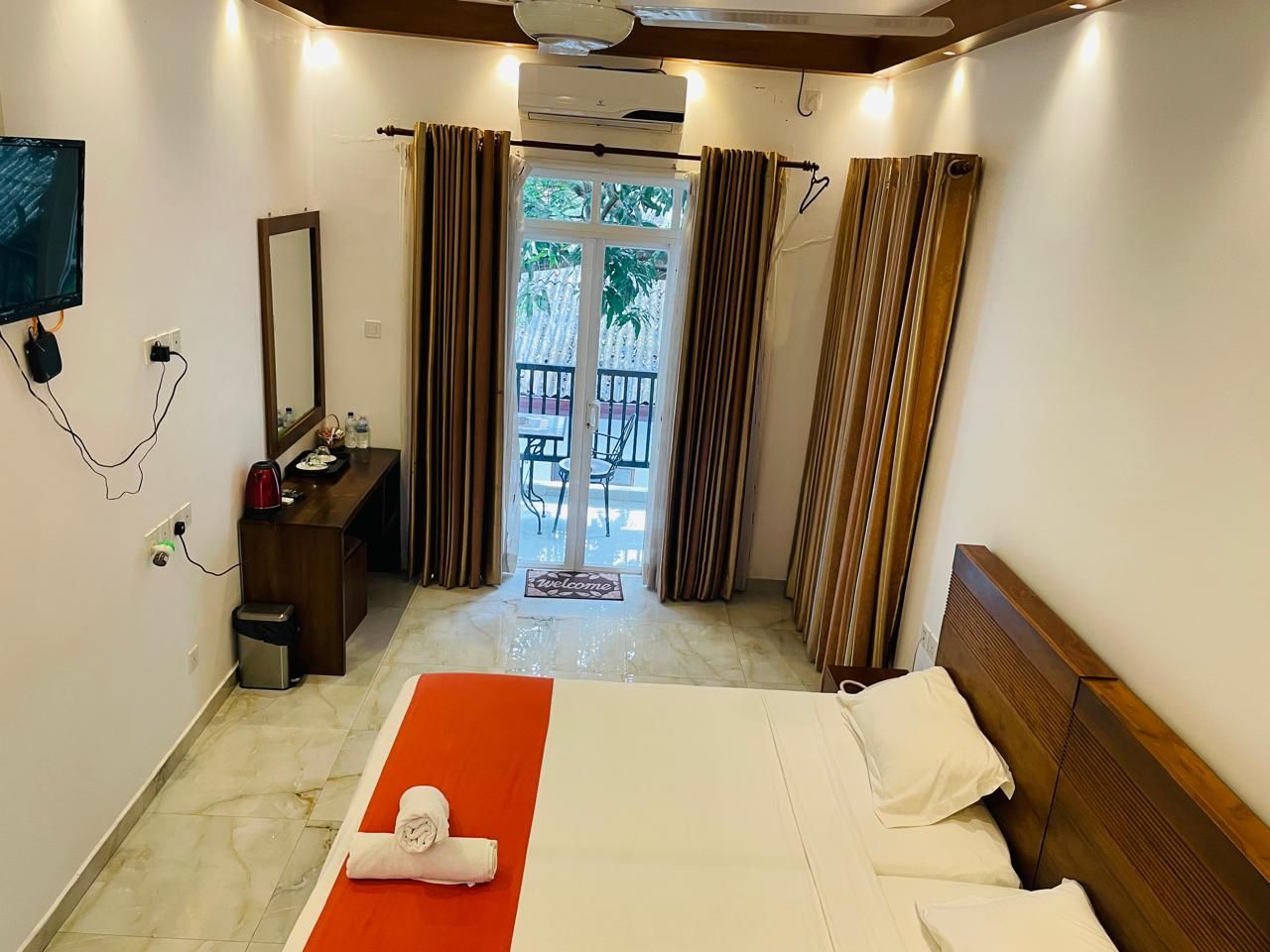 Ein Hotelzimmer mit Bett, Schreibtisch, Spiegel und Blick ins Freie.