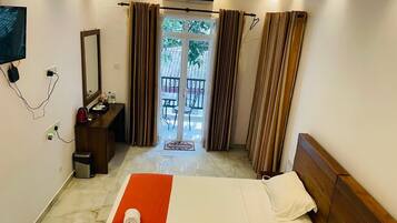 Ein Hotelzimmer mit Bett, Schreibtisch, Spiegel und Blick ins Freie.