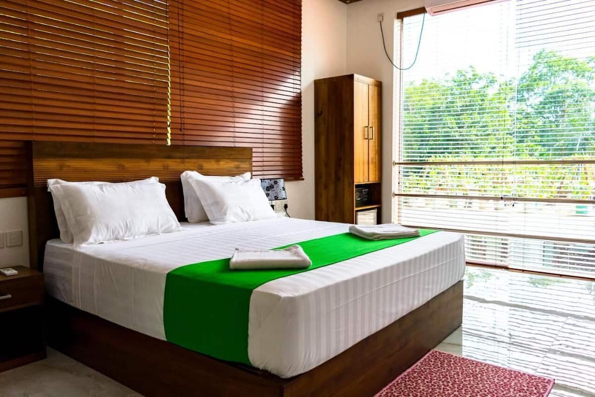 Un dormitorio moderno con cabecera de madera, colcha verde y vistas al exterior.