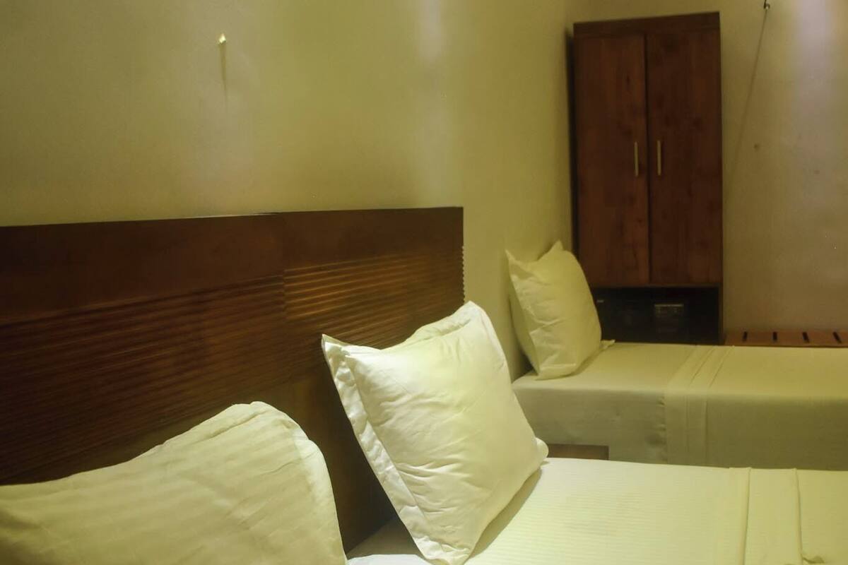 Un dormitorio con dos camas, cabecero de madera y un armario.