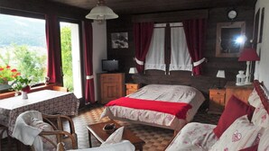 A cozy bedroom with a bed, a chair, a table, and a view of the outdoors. - Coquet Studio (Praz-sur-Arly)