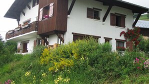 A two-story chalet with wooden balconies, white walls, and brown shutters. - Coquet Studio (Praz-sur-Arly)