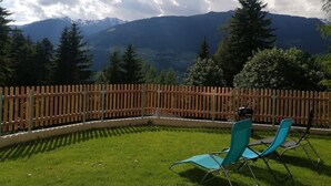 A patio with two blue chairs, a wooden fence, and a view of mountains. - Newly built in 2020, modern furnishings, quiet location, 2 bathrooms, sauna (Ramsau im Zillertal)