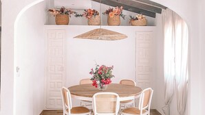 Un comedor con una mesa redonda de madera, sillas blancas y una lámpara colgante.