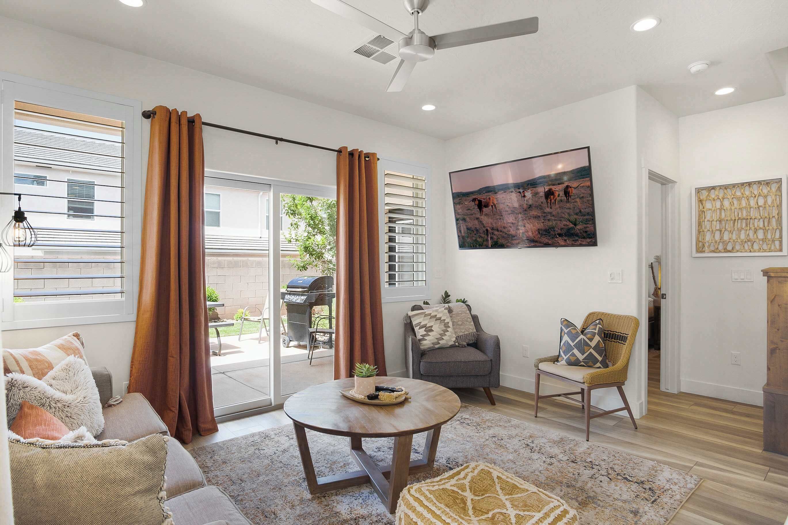 A spacious living room with a large window, a ceiling fan, and a dining area with a table and chairs.