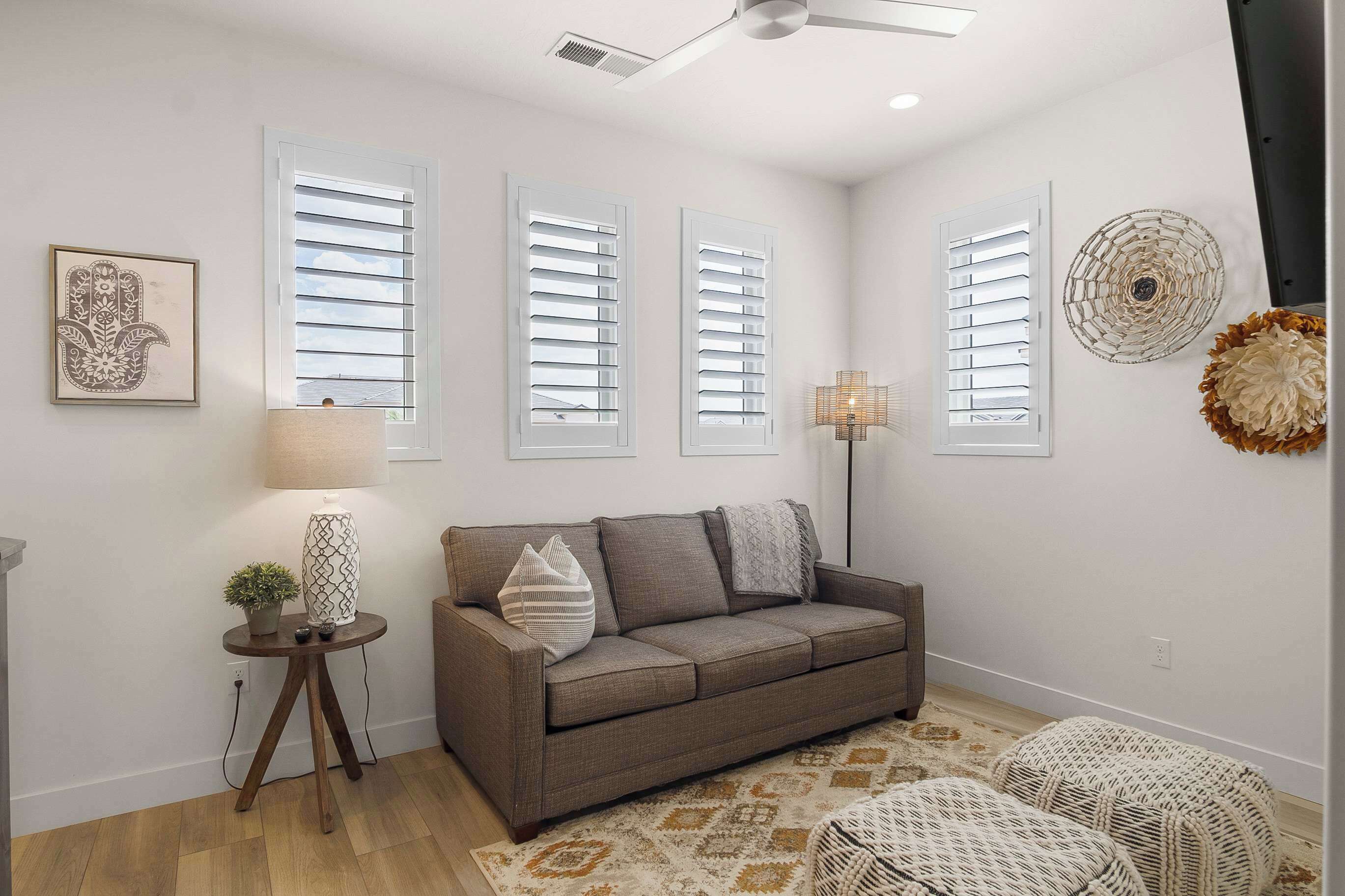 A living room with a sofa, a lamp, and a decorative wall piece.