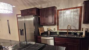 Una cocina moderna con armarios de madera oscura, electrodomésticos de acero inoxidable y una encimera de granito negro.