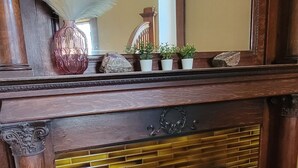 Una repisa de madera con un espejo decorativo, un florero y pequeñas macetas.