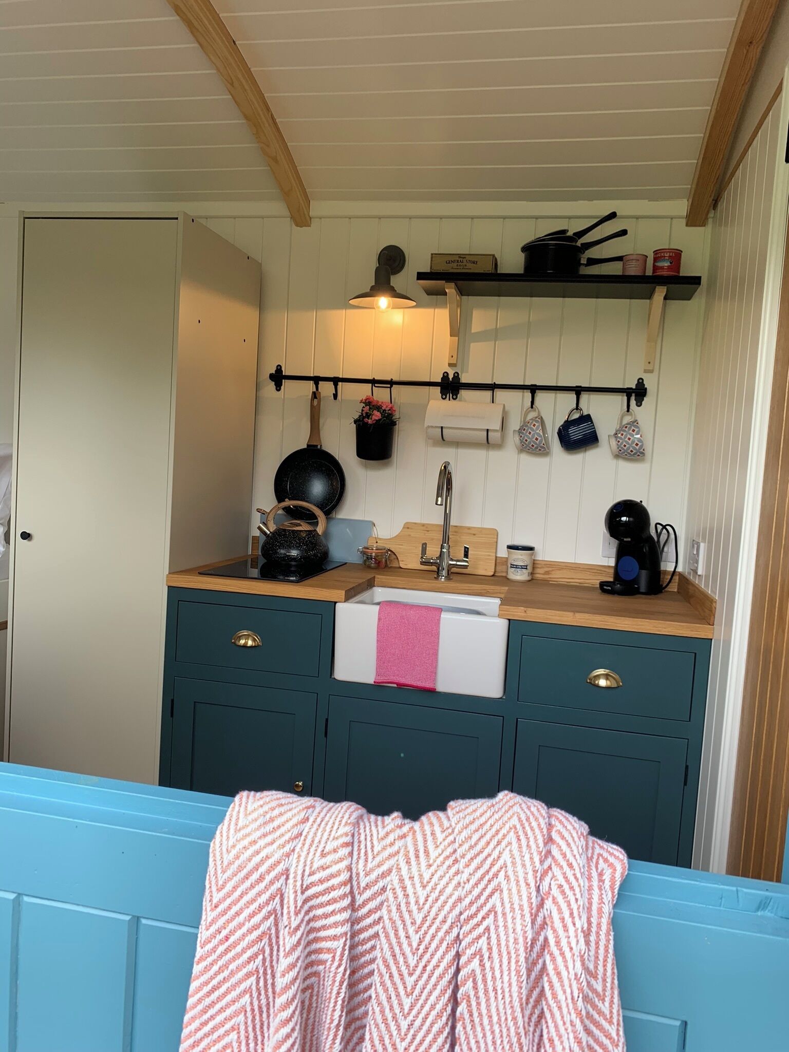 A compact kitchen with a wooden countertop, a sink, and a hanging pot rack.
