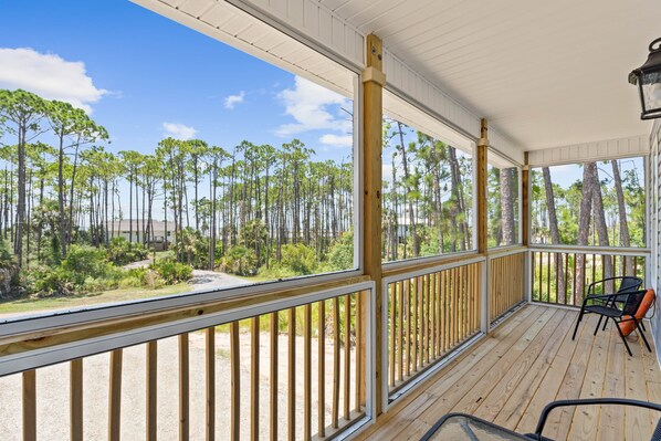 A covered porch with a view of a forest.